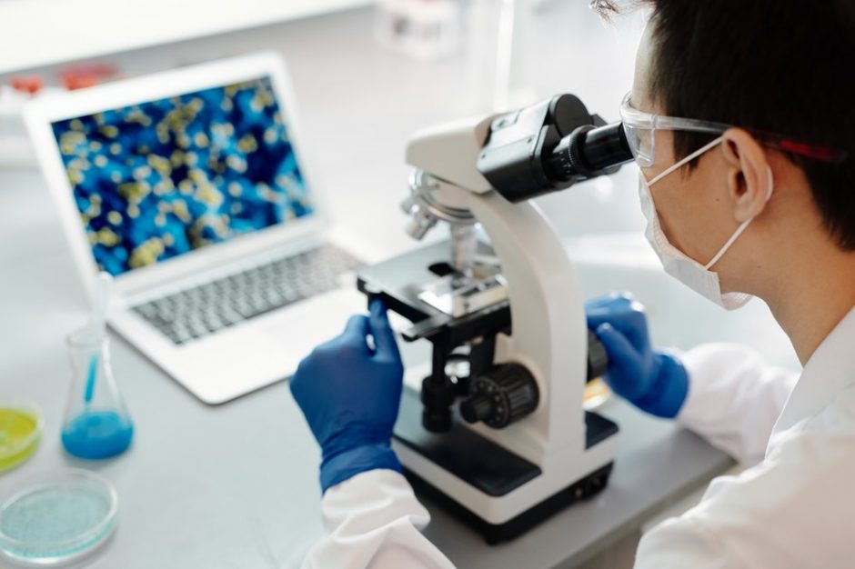man staring into microscope in lab